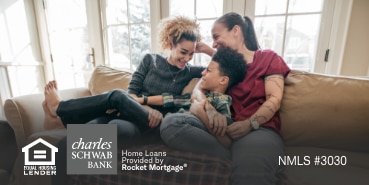 Mom, daughter, and son cuddling on couch smiling