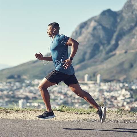 A fit man runs on a desert road.