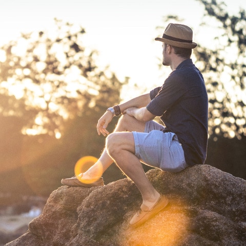 A person gazes across a harbor at the sun setting in the distance.